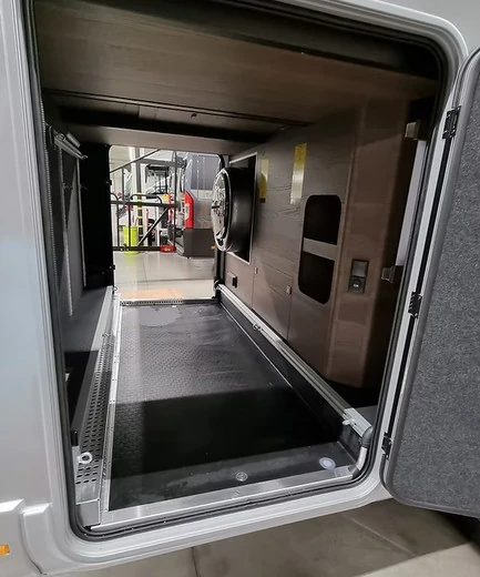 Blick durch die Heckgarage eines Adria Wohnmobils auf eine seitlich eingebaute tinyWASH Waschmaschine – Herstellerbeispiel