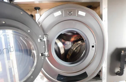 Geöffnete Tinywash Waschmaschine mit Blick auf die Waschtrommel nach dem Einbau im Wohnmobil